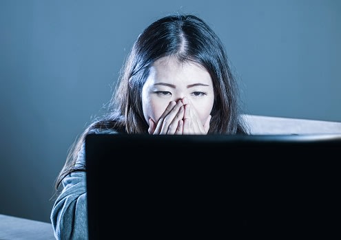 young worried Asian Korean student girl looking depressed and desperate studying with laptop computer in stress for exam feeling frustrated stalked and harassed on internet bullying