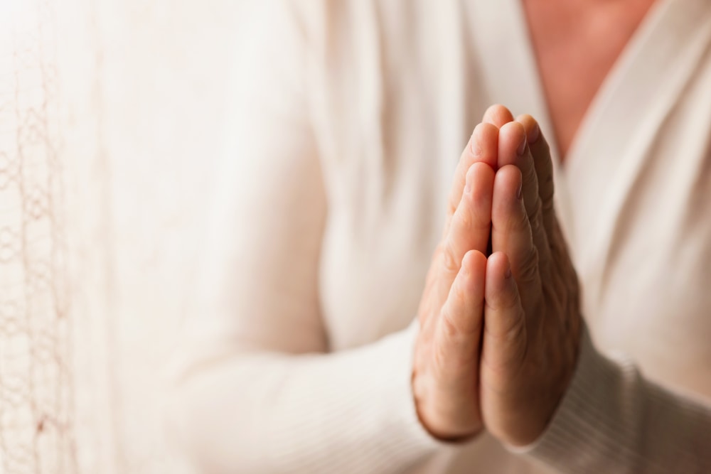 Woman folding hands in prayer