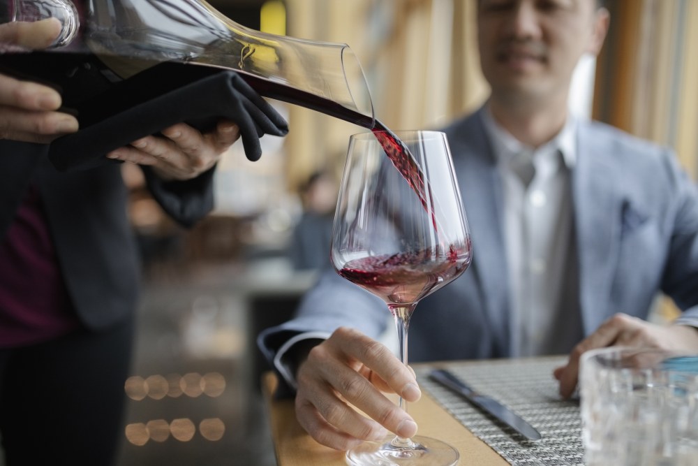 No more foie gras with that Chambertin a waiter filling a glass of red wine