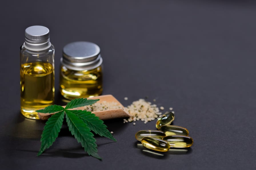 Bottles of cannabis oil, hemp leaves, and capsules on a dark background, illustrating the intersection of cannabis products and legal implications related to DUI charges.